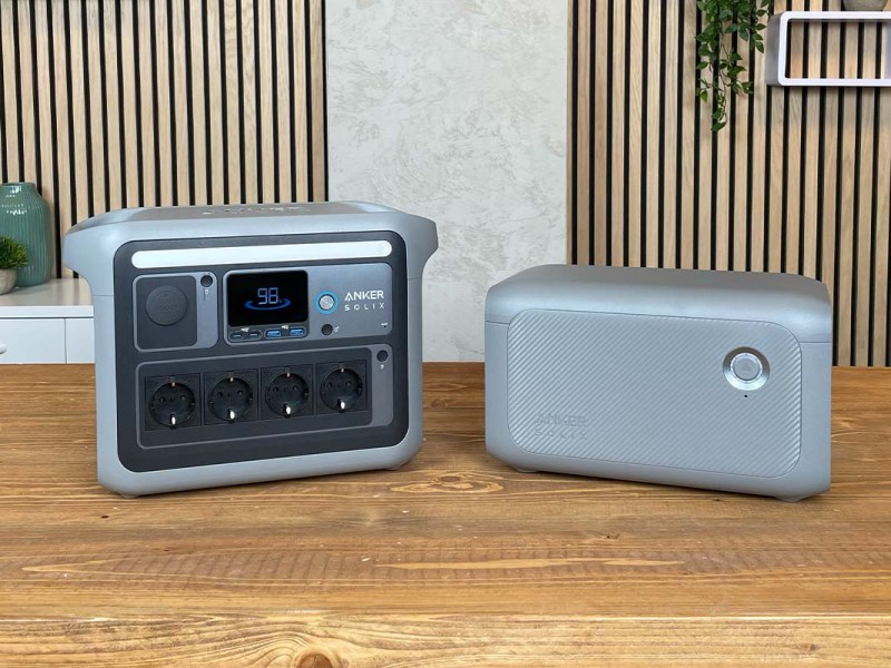 Die Anker Solix C1000 mit Erweiterungs-Akku auf einem Holztisch vor wohnlichem Hintergrund.